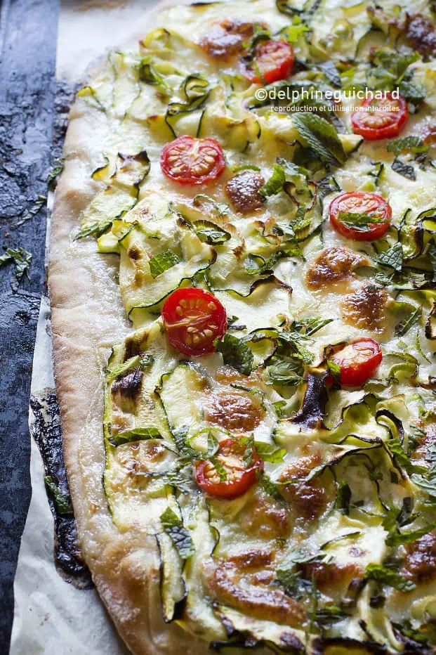 Pizza courgette, mozzarella, menthe : saveurs et subtilité. 1 Une pizza généreusement recouverte de courgettes marinées, mozzarella, tomates pour la pointe de sucré, et agréablement ponctuée de notes de menthe fraîche.