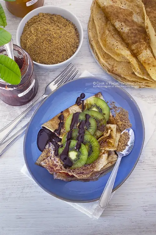 Pour le goûter, 2 crêpes vegan à la confiture, coulis de chocolat noir, sucre de canne complet et quelques tranches de kiwis pour la fraîcheur.